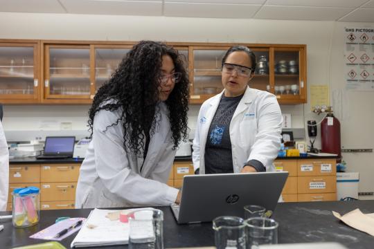 Faculty and student in a lab looking at a laptop